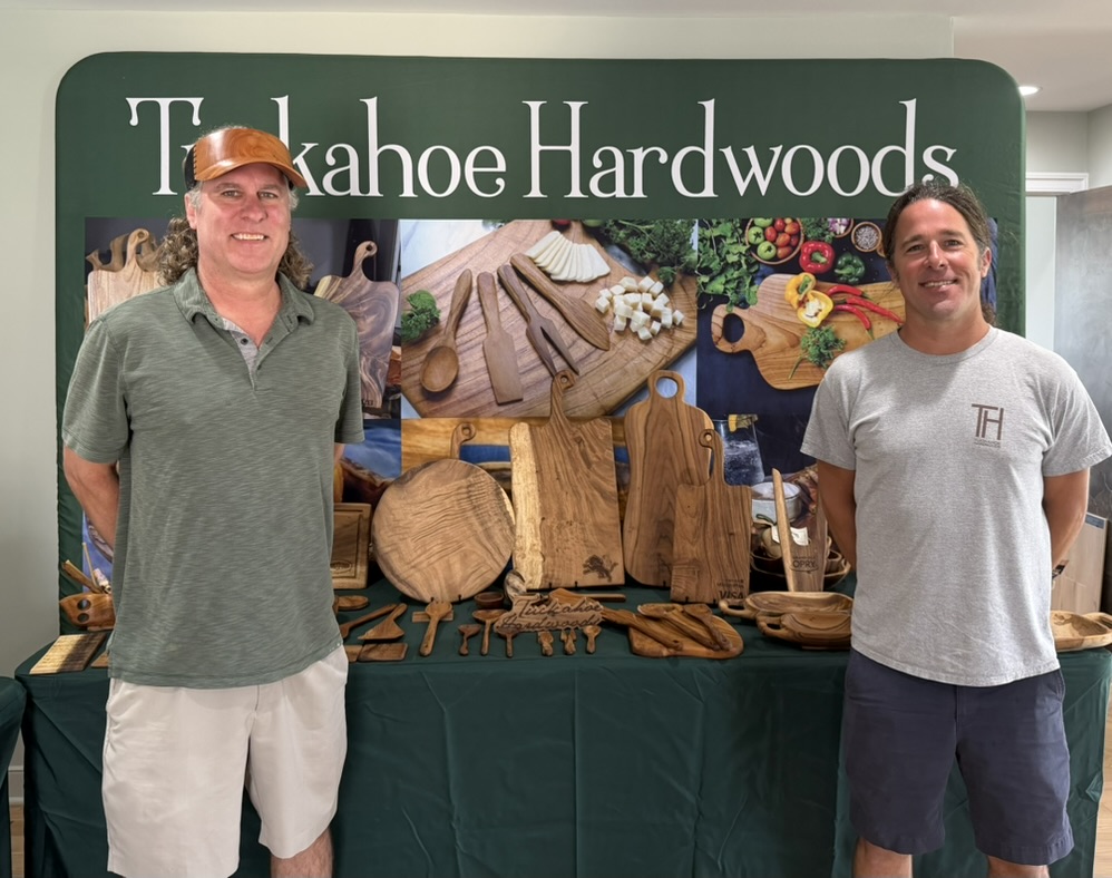 Tuckahoe Hardwoods team at a showroom display with wooden boards, utensils, and charcuterie goods